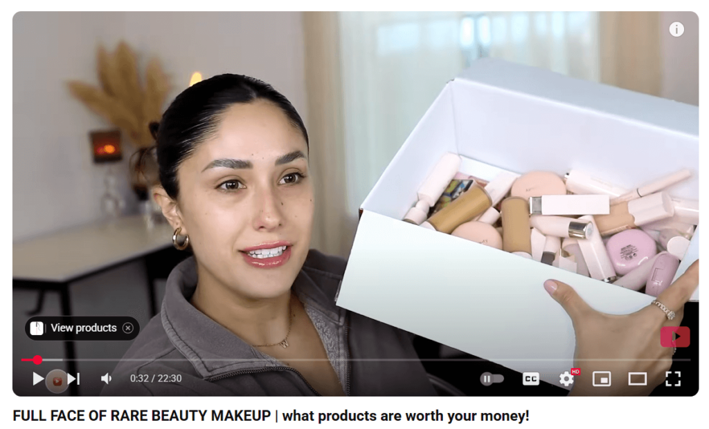 YouTube influencer holding a box of beauty makeup during a product review video.